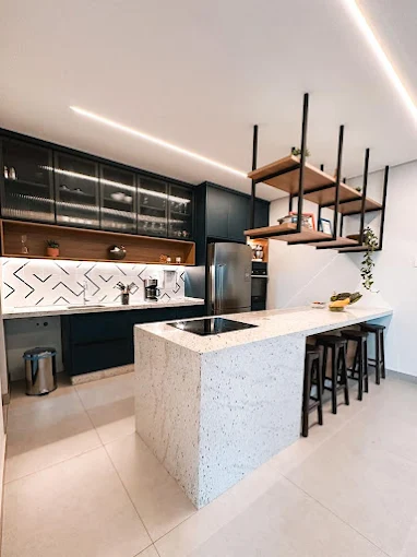 Cozinha com bancada em pedra clara, cooktop na ilha e armários superiores de vidro