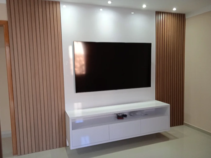 Painel ripado de madeira com rack suspenso branco e TV na sala