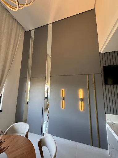Sala de jantar com painel canelado, arandelas douradas e mesa redonda